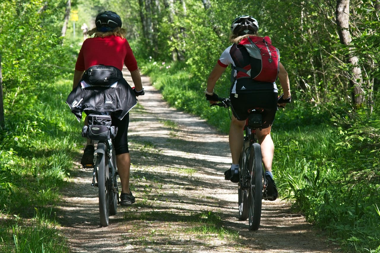 Two people riding bikes on a dirt trail